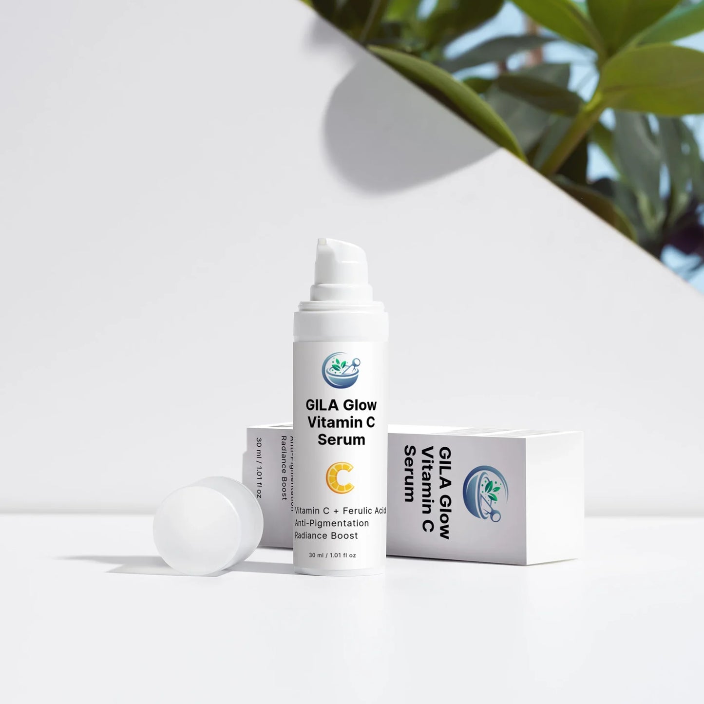 An image of the GILA Glow Vitamin C Serum with lid off, and the box on its side. It's on a white outdoor background, with shrubs peeking up from behind