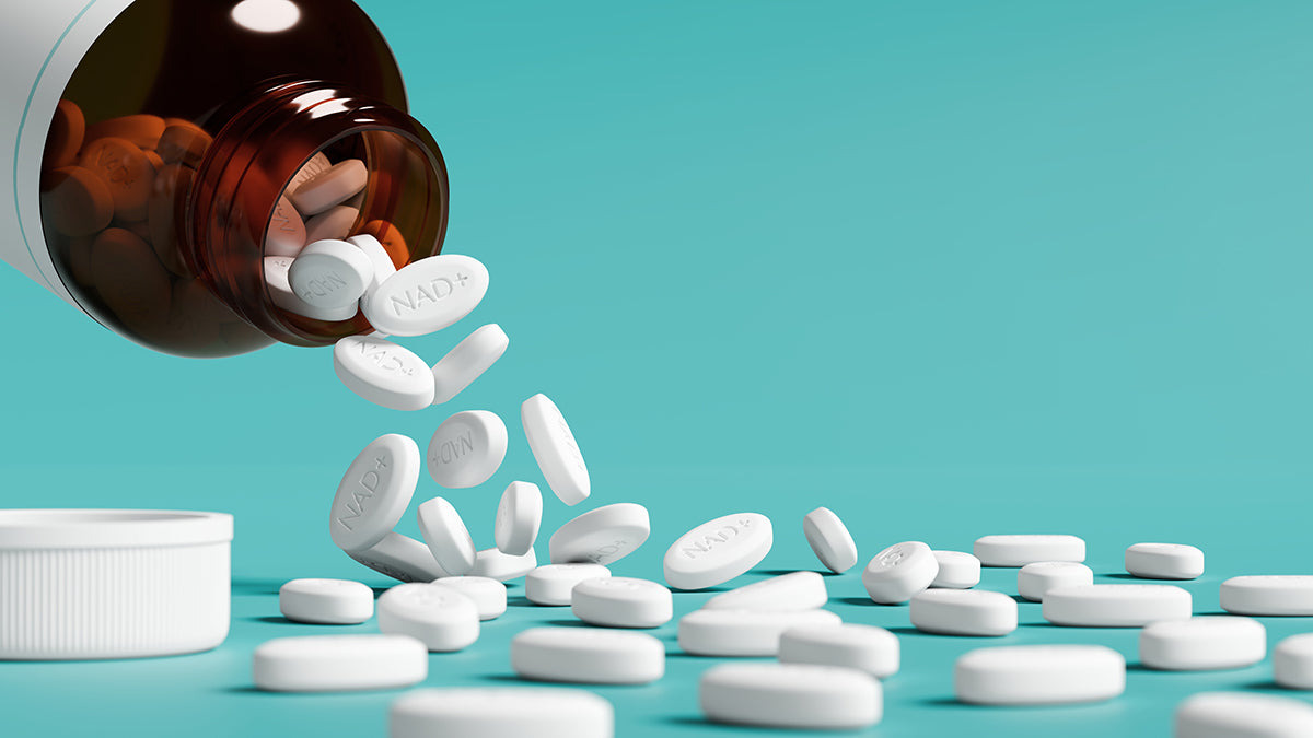 White NAD+ pills spilling out of a brown bottle onto a light blue background