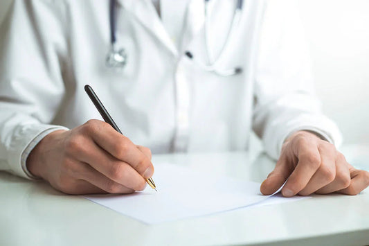 A close up of a medical professional in a white lab coat writing on a piece of paper