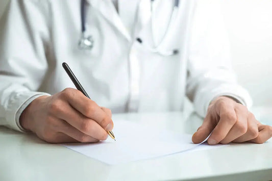 A close up of a medical professional in a white lab coat writing on a piece of paper