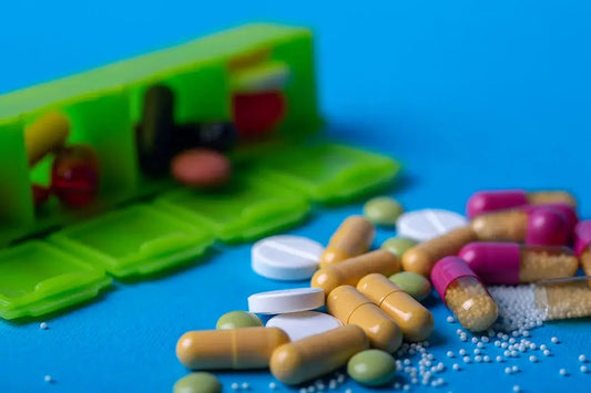 An image of a pill organizer with many different pills and capsules spilled out